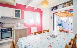 Eine Küche mit weißen Schränken, einer Holz Arbeitsplatte und einem Backofen. Ein Esstisch mit Stühlen und einer blumigen Tischdecke ist ebenfalls vorhanden.