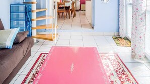 Un interior moderno con una escalera de madera, un comedor y una cocina visible a través de una puerta abierta.