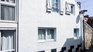 Un edificio blanco con varias ventanas, una antena parabólica y un letrero pequeño.