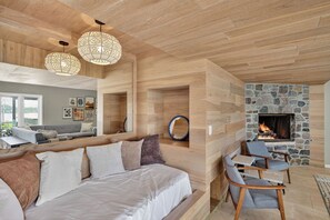 Ein modernes Wohnzimmer mit Kamin aus Stein, Holzboden und einer Couch mit Kissen.