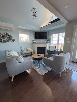 A living room with a fireplace, a flat-screen TV, and a ceiling fan.