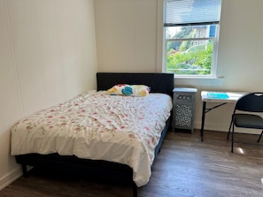A bedroom with a bed, a desk, and a chair.
