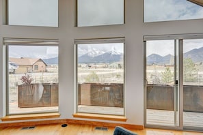 Une piĂšce dotĂ©e de grandes fenĂȘtres, dâun plancher en bois et offrant une vue sur un paysage montagneux.