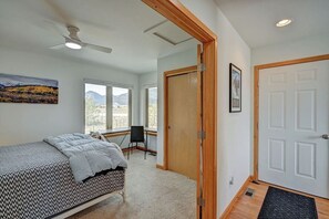 A bedroom with a bed, a chair, a desk, and a door.
