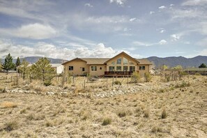 A single-story house with a large front porch and a mountain backdrop.