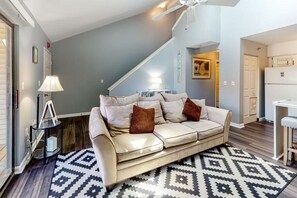 Ein Wohnzimmer mit einer Couch, einem Teppich mit Muster und einem Deckenventilator.