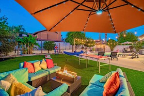 Ein Terrassenbereich im Freien mit Sitzgelegenheiten, einer Feuerstelle und Lichterketten.