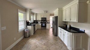 A spacious kitchen with white cabinets, a stainless steel refrigerator, and a tiled floor. - Lux- Minimum 2 -Lexington With-Riverwalk & CAE (West Columbia)