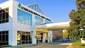 A modern medical center building with a clear entrance, a covered parking area, and a visible address. - Lux- Minimum 2 -Lexington With-Riverwalk & CAE (West Columbia)