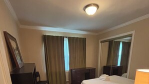 A hotel room with a bed, a desk, a chair, a dresser, a lamp, and a mirror. - Lux- Minimum 2 -Lexington With-Riverwalk & CAE (West Columbia)