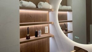 Ein modernes Badezimmer mit Holzregalen, einem großen Spiegel und einer Toilette.