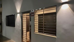 Ein Korridor mit einer Tür und einem Fenster, beide mit Sicherheitsrollläden, und einem Schild, das ein Alarmsystem anzeigt.
