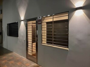 Ein Korridor mit einer Tür und einem Fenster, beide mit Sicherheitsrollläden, und einem Schild, das ein Alarmsystem anzeigt.