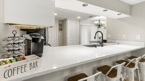 Una cucina moderna con angolo caffè, un'isola grande e sgabelli da bar.