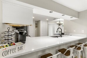 A modern kitchen with a coffee bar, a large island, and bar stools.