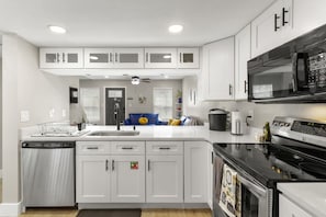 Una cocina moderna con armarios blancos, estufa negra y microondas.