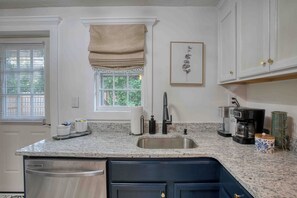 A kitchen with a granite countertop, stainless steel sink, and a coffee maker. - Castle Street Retreat - The Rustic Whiskey (Wilmington)