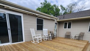 Eine Holzterrasse mit Gartenmöbeln, einer Schiebetür und einem kleinen Fenster.