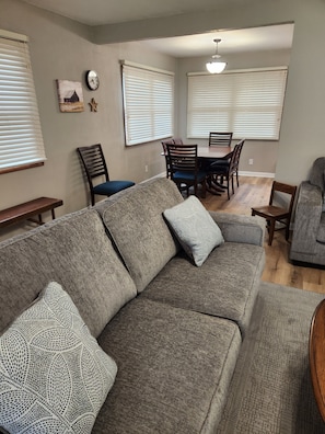 A living room with a gray sectional sofa, a dining table with chairs, and a ceiling fan. - A GREAT 4 Bedroom 2 Bath home with lots of room for fun It's The American Dream! (Boone)