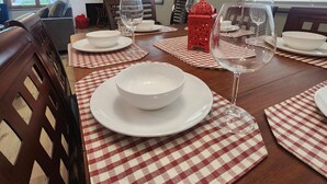 Ein Esszimmer mit einem Holztisch, gedeckt für vier Personen, karierten Platzsets, weißen Tellern und Weingläsern.