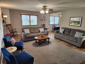 A living room with a sofa, chairs, a coffee table, a dining table, and a ceiling fan. - A GREAT 4 Bedroom 2 Bath home with lots of room for fun It's The American Dream! (Boone)