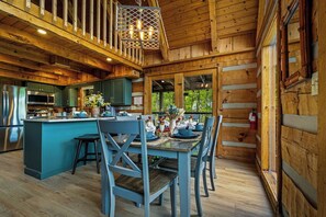 Ein Holzblockhaus-Interieur mit Küche, Essbereich und großen Fenstern.