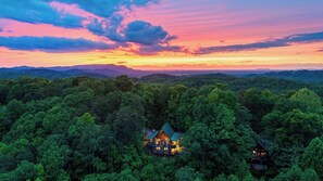 Eine Lodge, umgeben von dichtem Wald, mit einem auffälligen Gebäude mit einem grünen Dach und zahlreichen Fenstern.