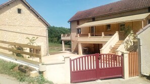Ein zweistöckiges Gebäude mit einer Sandsteinfassade, einem roten Tor und einer Treppe, die zu der oberen Etage führt.