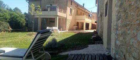 A house with a garden, a lounge chair, and a stone wall.