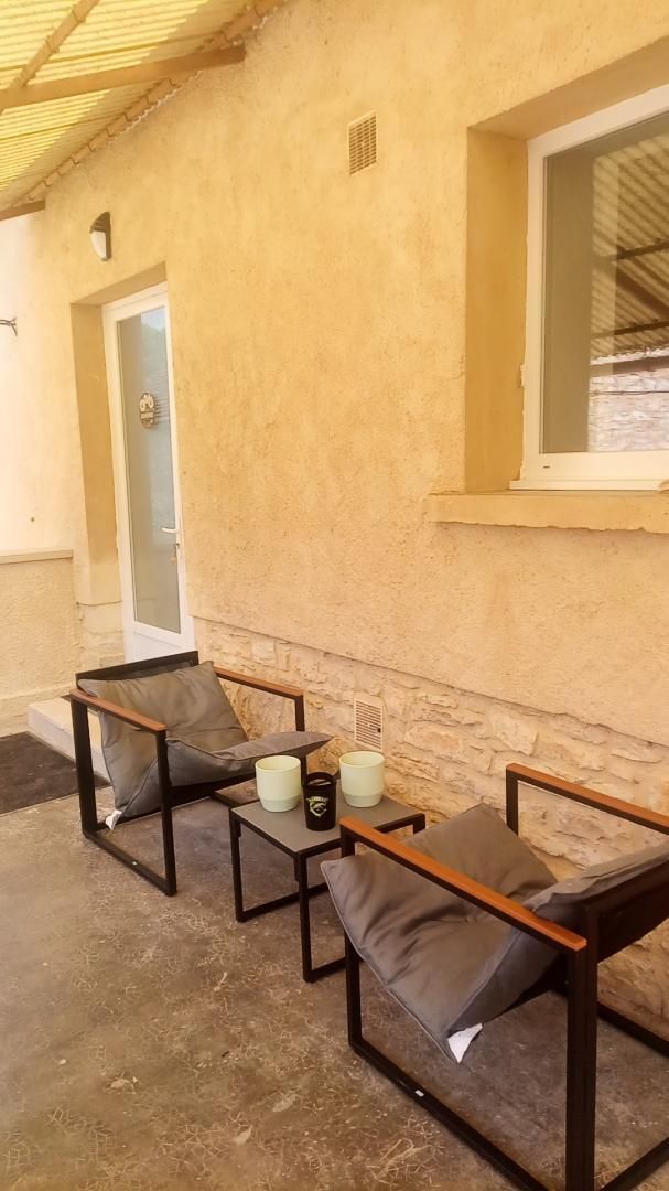 Un espace extérieur aménagé avec deux chaises et une petite table, une porte et une fenêtre.