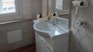 Un baño con lavamanos blanco, espejo y armarios de almacenamiento.