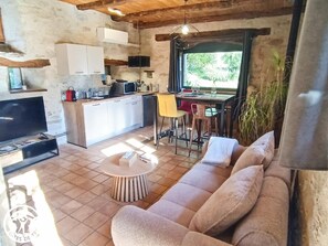 Ein gemütlicher Wohnbereich mit einer Couch, einem Fernseher, einem Esstisch und einer Küche im Hintergrund.