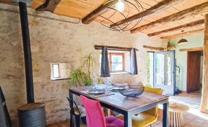 Ein rustikaler Essbereich mit Holztisch, Stühlen und einer Hängelampe.
