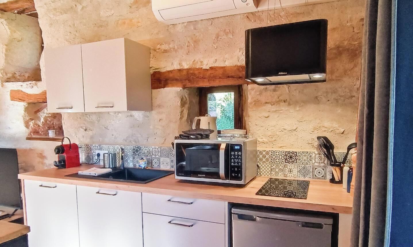 Una cocina con microondas, un ventanal pequeño y televisor montado en la pared.