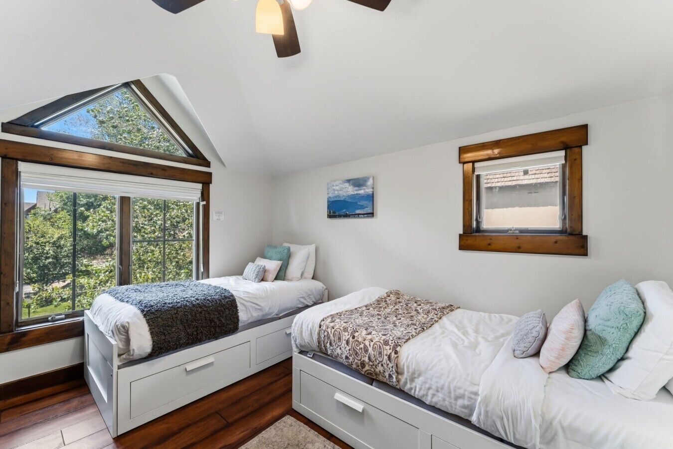 Une chambre avec deux lits, une lucarne et une vue sur la verdure.