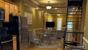 A spacious kitchen with modern appliances, a dining area with a round table and chairs, and a staircase leading to an upper level. - Free Parking, Walking Distance, Camden Yards, M&T Stadium, U of MD, Convention (Baltimore)