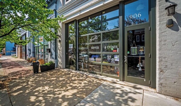 A storefront with large glass windows, a sign for 'Swirl' cocktails, supper, and events, and the number 906 on the door.