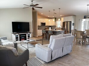 A modern living room with a sofa, TV, and dining area with chairs and a table. - Getaway to your home away from home! (North Port)