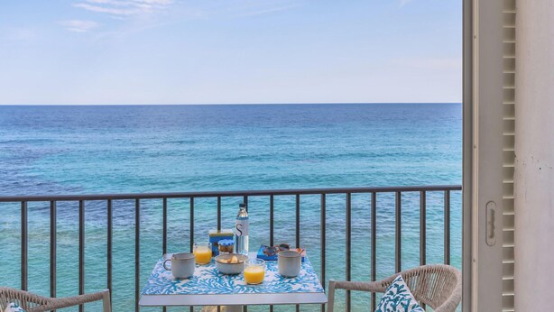 Un balcon avec une table préparée pour le petit-déjeuner, donnant sur la mer.
