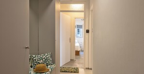 Een gang die leidt naar een slaapkamer met een bed, nachtkastje en een deur met slot.