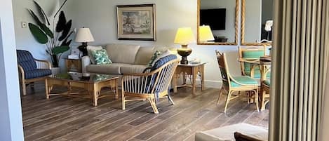 Uma sala de estar com ventilador de teto, área de jantar com cadeiras, sofá e mesa.