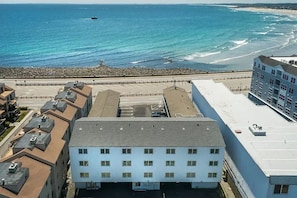Un edificio costiero con diversi piani, un parcheggio e vista sull'oceano e sulla spiaggia.