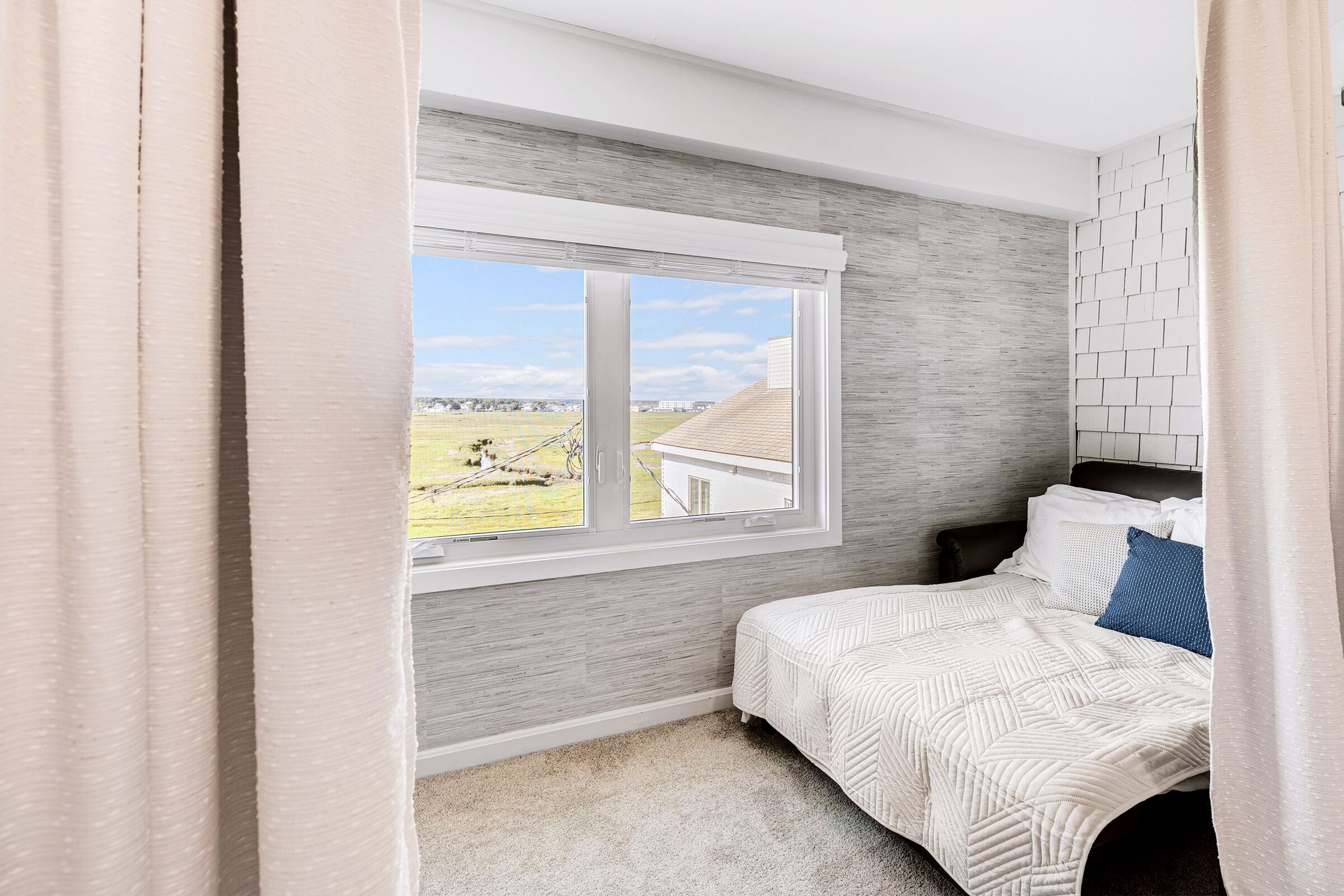 A bedroom with a bed, a window, and a view of the outdoors.