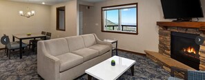 Una sala de estar con sofá, mesa de centro, chimenea, televisión y un comedor con sillas y una mesa.
