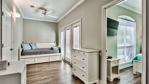 Een slaapkamer met een bed, een kaptafel, nachtkastje en een plafondventilator.