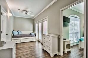 Ein Schlafzimmer mit Bett, Kommode, Nachttisch und Deckenventilator.