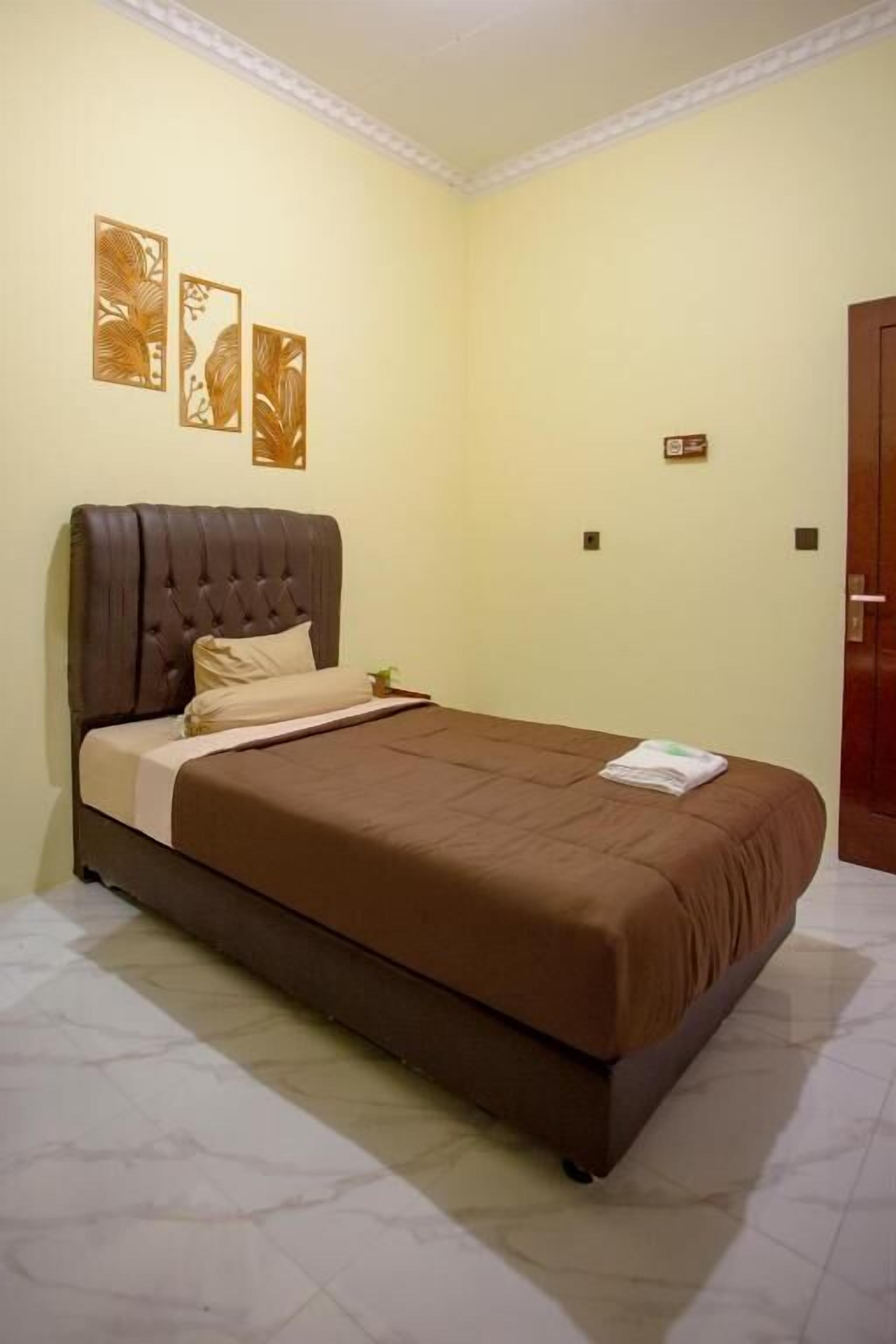 A bedroom with a large bed, a headboard, and a wall-mounted artwork.