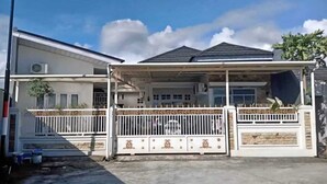 A residential house with a covered porch, a gated entrance, and a garage. - By The Padi - Homestay (Padang)
