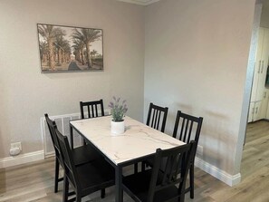 A dining area with a rectangular table, six chairs, a potted plant, and a framed picture on the wall. - Charming & Chic: Your Stylish Oasis for a Month-Long Retreat (Henderson)
