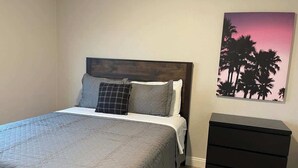 Ein Schlafzimmer mit einem Bett, einer Kommode und einer Wand mit einem Sonnenuntergangsgemälde.